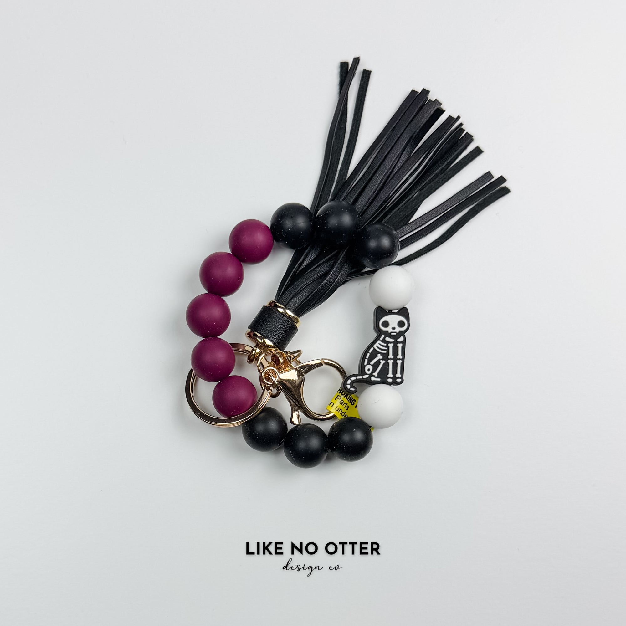 Keychain with beads and tassels on a light gray background.