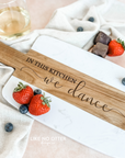 Acacia wood and marble charcuterie or serving board with engraving "in this kitchen we dance" on wood. Engraved and sold by Like No Otter Design Co