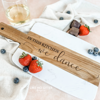 Acacia wood and marble charcuterie or serving board with engraving "in this kitchen we dance" on wood. Engraved and sold by Like No Otter Design Co