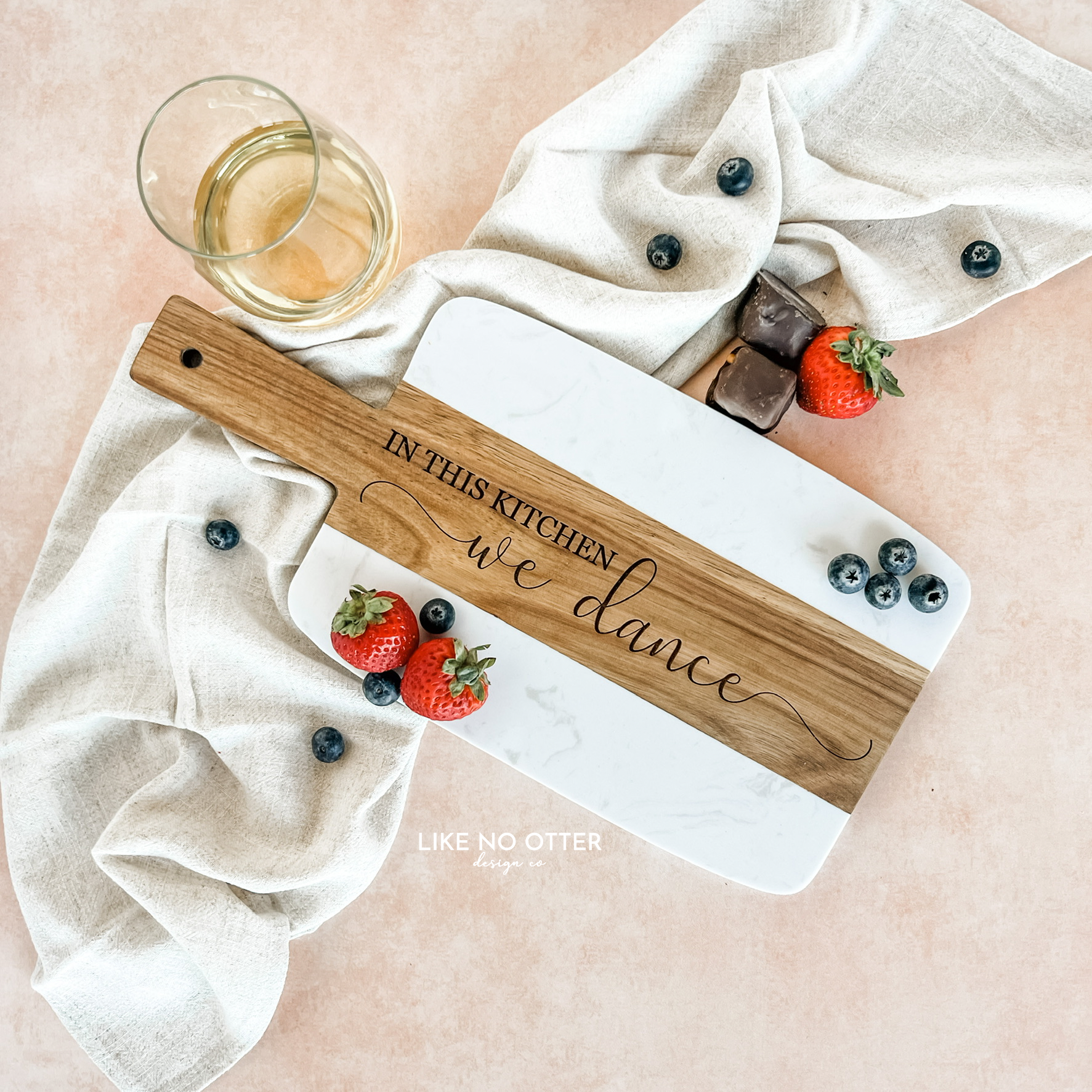 Acacia wood and marble charcuterie or serving board with engraving "in this kitchen we dance" on wood. Engraved and sold by Like No Otter Design Co